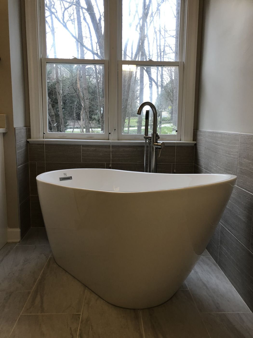 Freestanding soaking tub under a window with a floor-mounted tub filler — Triangle Home Handyman, Apex NC