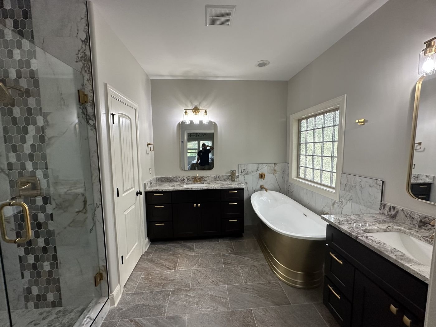 Brass freestanding tub with dark vanities and a hexagon tile shower accent — Triangle Home Handyman, Apex NC