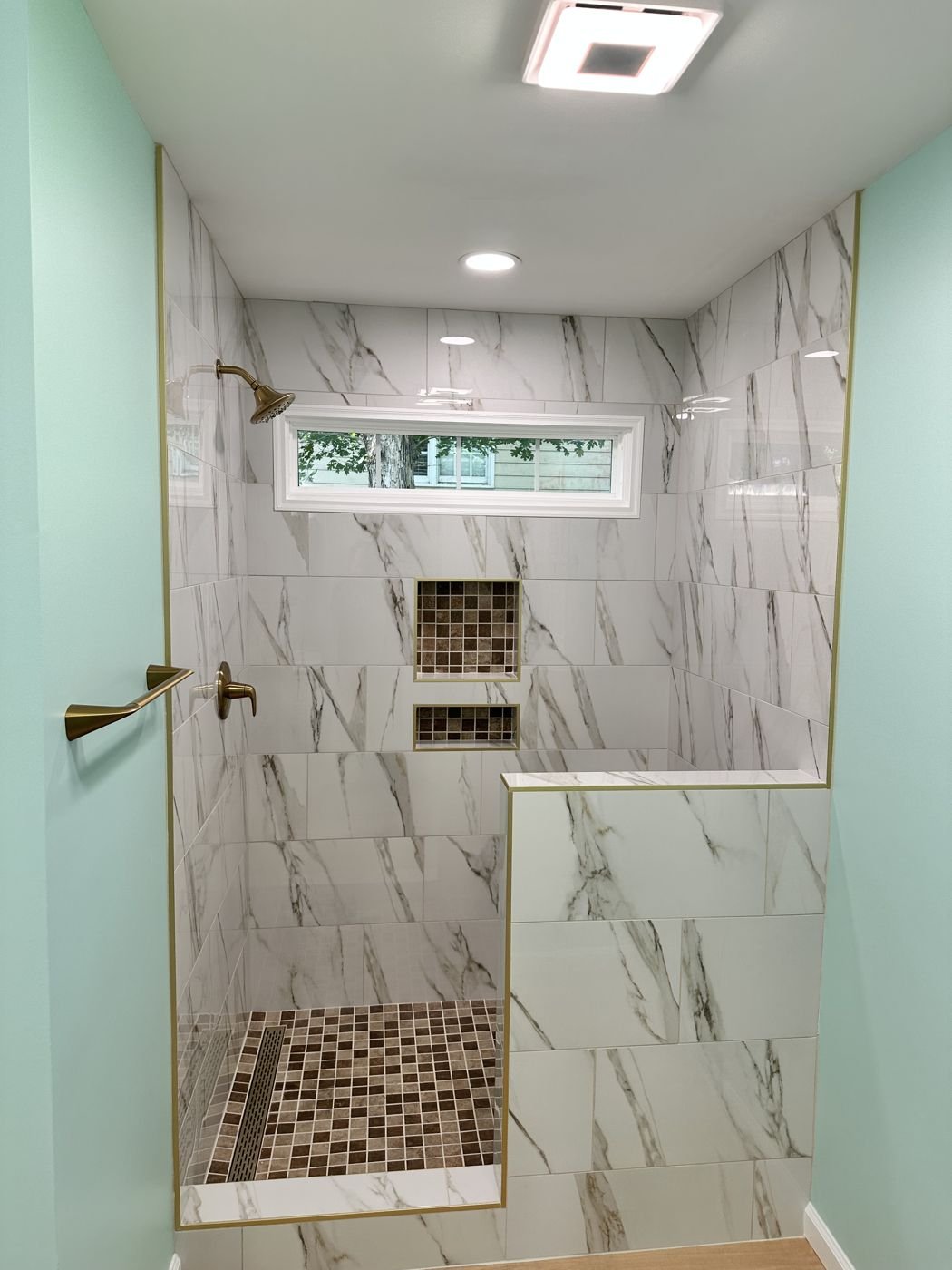 Walk-in shower with marble-look tile, brass shower head and mosaic floor — Triangle Home Handyman, Apex NC