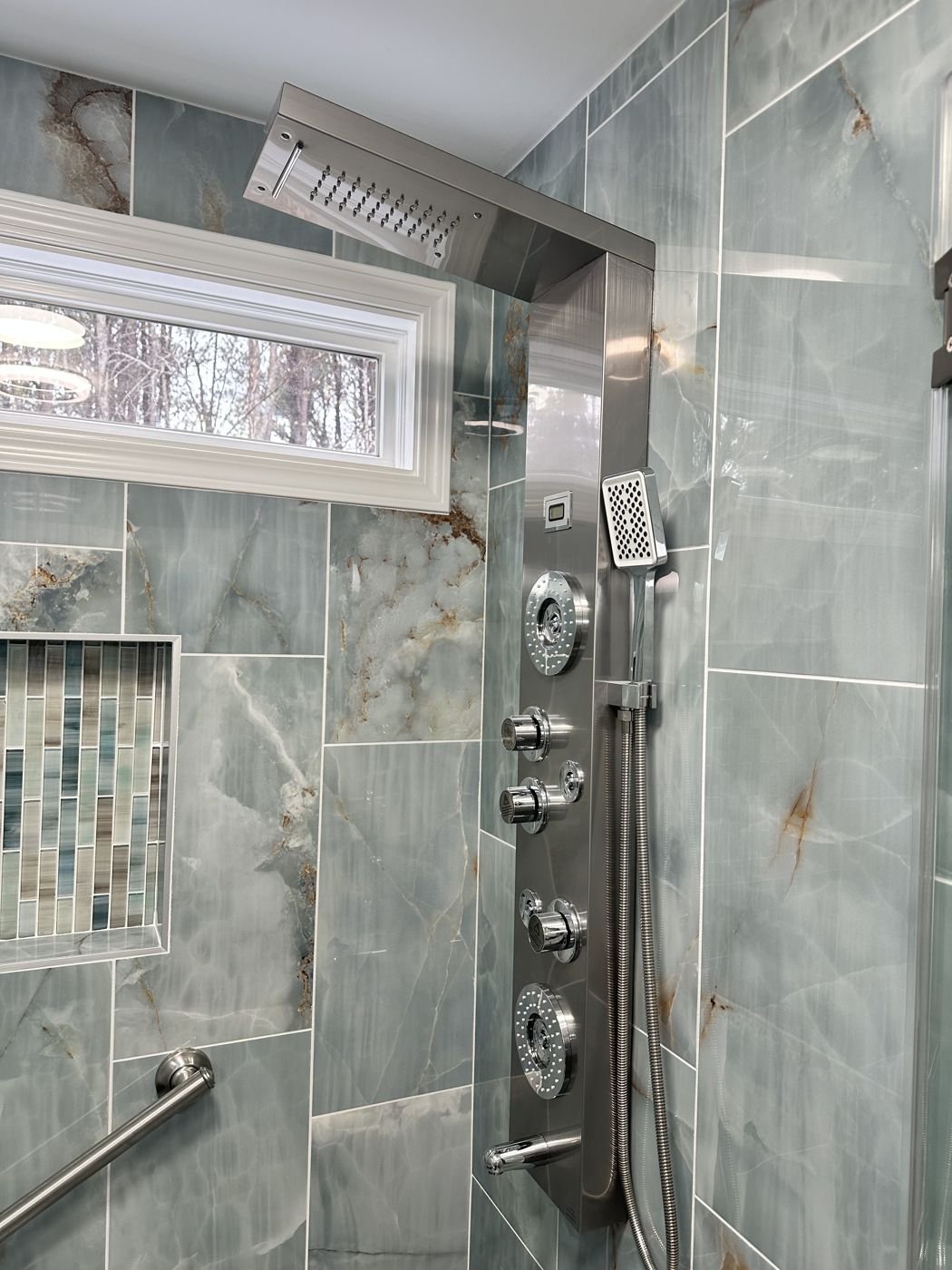 Blue-green marble-look shower tile with a stainless shower panel and body jets — Triangle Home Handyman, Apex NC
