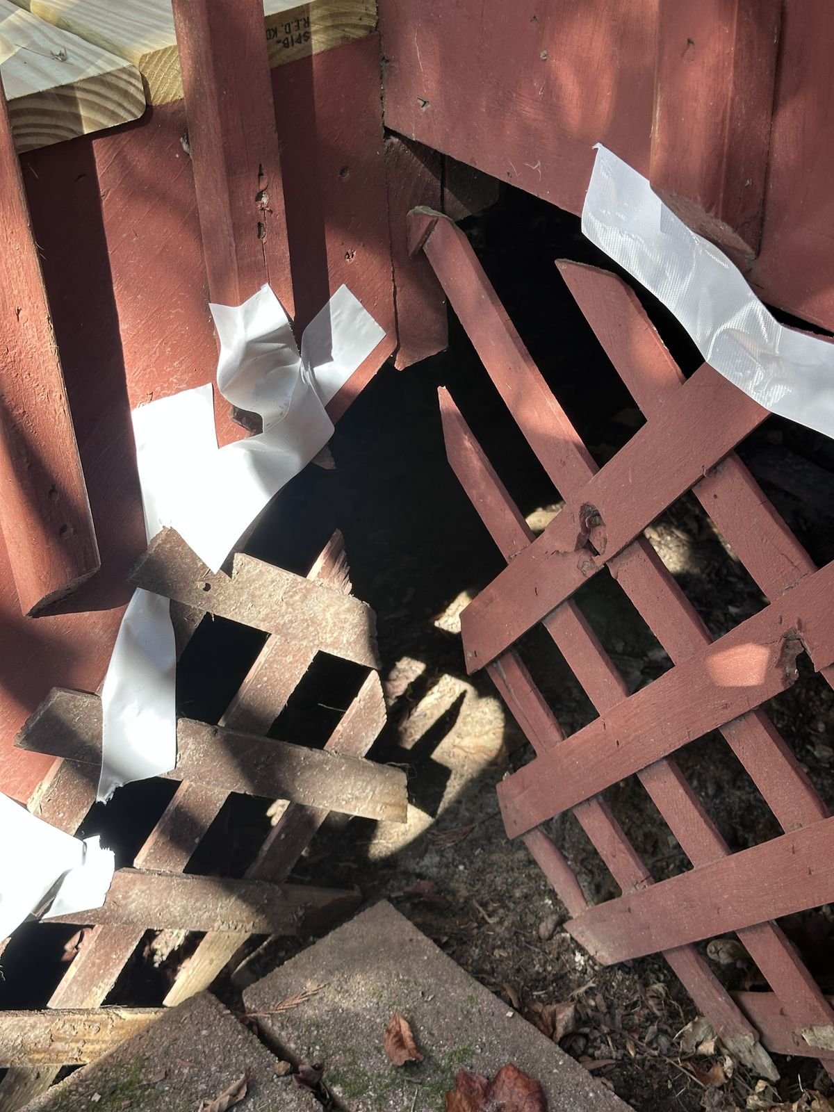 Broken and detached lattice skirting beside the deck stairs before repair