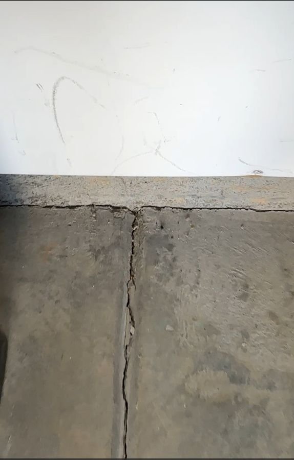 Wide crack where a garage floor slab meets the wall, before repair, Apex NC — Triangle Home Handyman, Apex NC