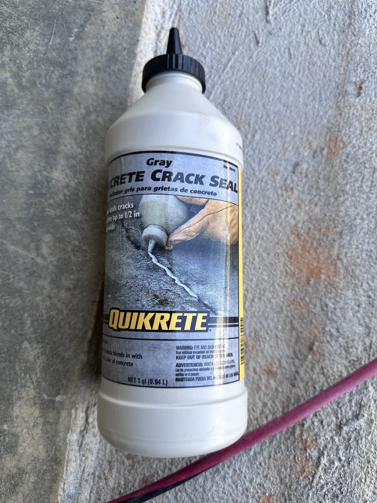 Bottle of Quikrete Gray Concrete Crack Seal on a garage floor — Triangle Home Handyman, Apex NC