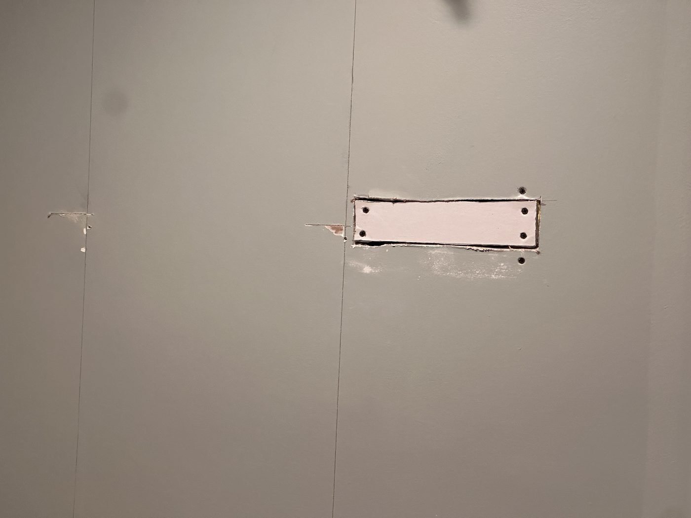 Drywall patch screwed into place over an outlet cutout