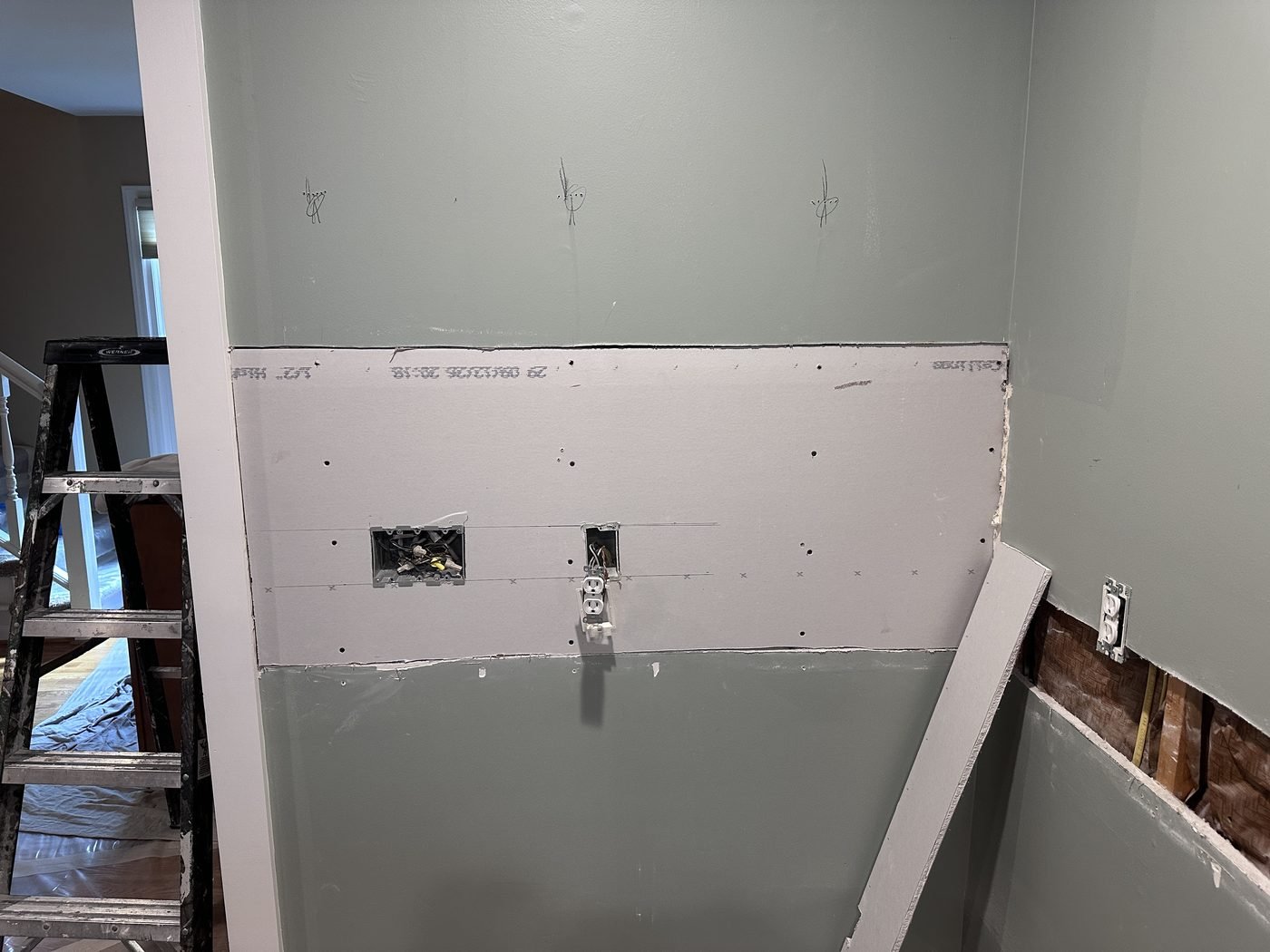New drywall sheet installed with outlet cutouts