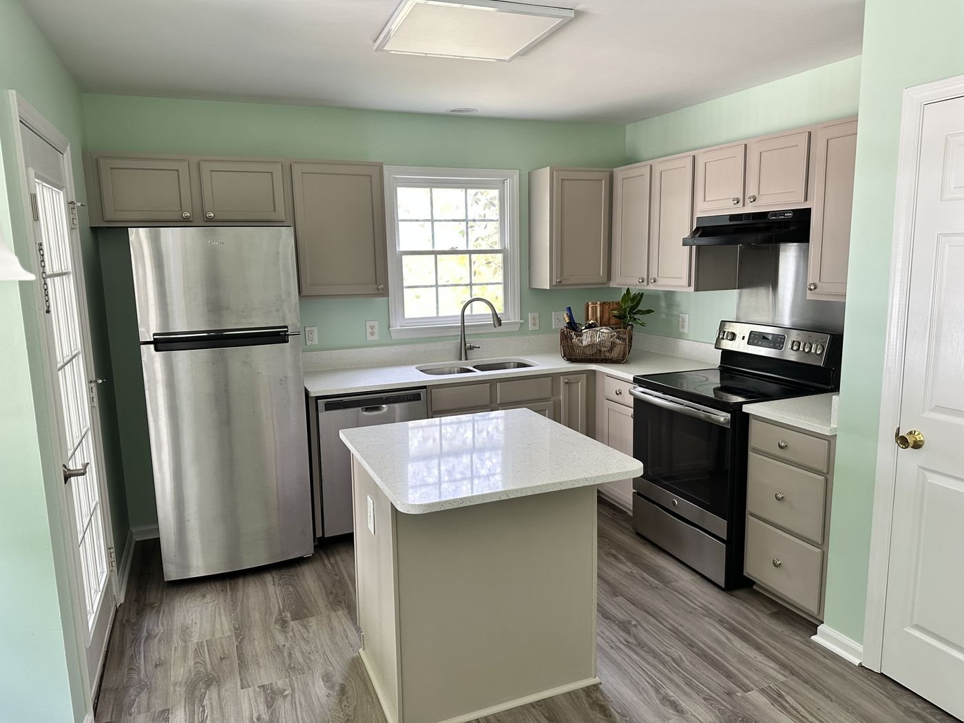 Compact kitchen with greige cabinets, a white island and stainless appliances — Triangle Home Handyman, Apex NC