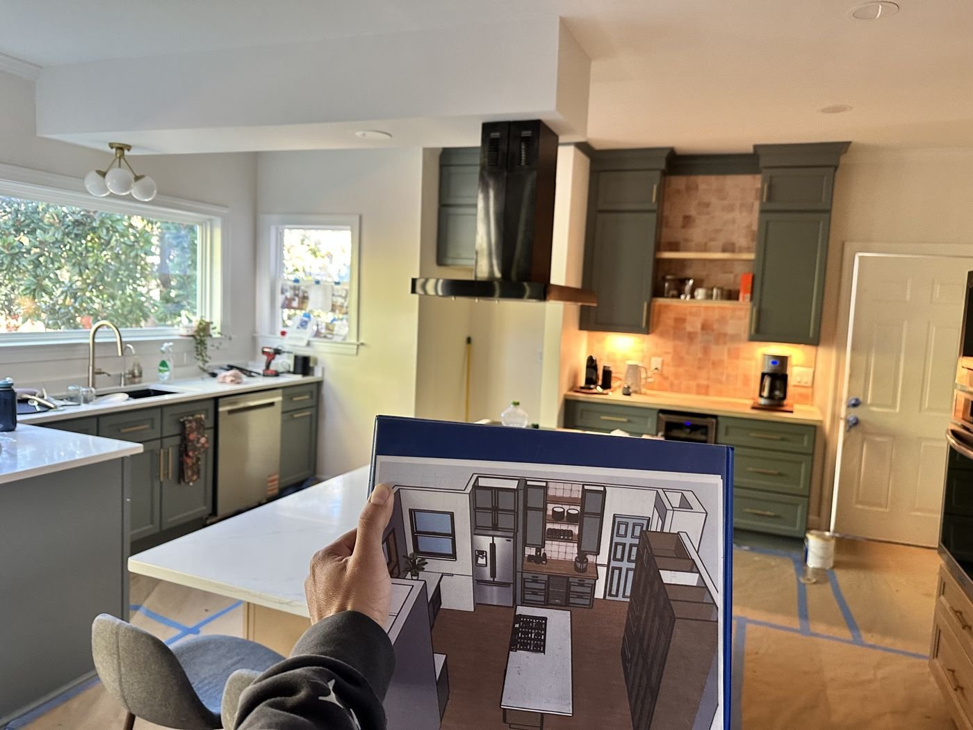Kitchen remodel in progress with the design plan held up next to green cabinets — Triangle Home Handyman, Apex NC